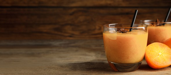 Image of Tasty persimmon smoothie with anise and straw on wooden table, space for text. Banner design