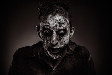 Photo of Scary zombie on dark background, black and white effect. Halloween monster