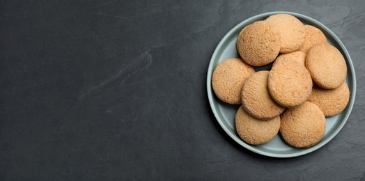 Photo of Delicious sugar cookies on black table, top view. Space for text
