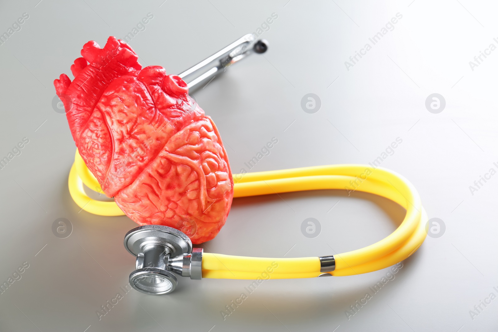 Photo of Stethoscope and model of heart on gray background. Heart attack concept