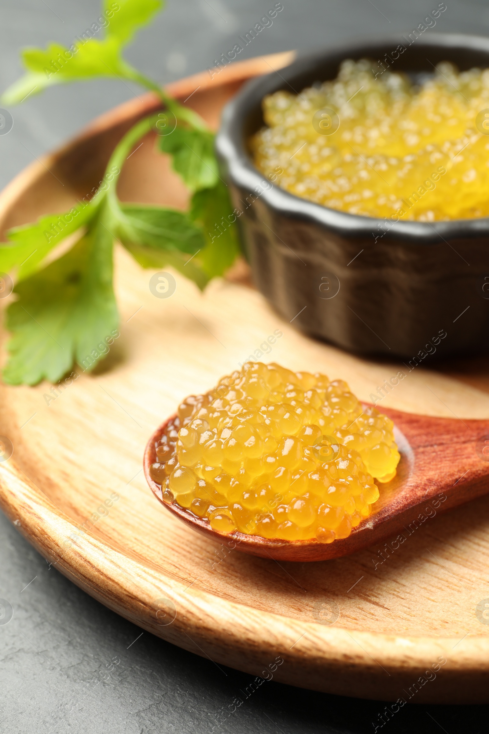 Photo of Fresh pike caviar and parsley on grey table, closeup