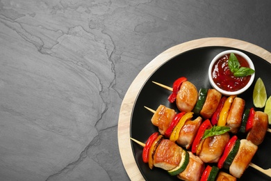 Delicious chicken shish kebabs with vegetables and sauce on grey table, top view. Space for text