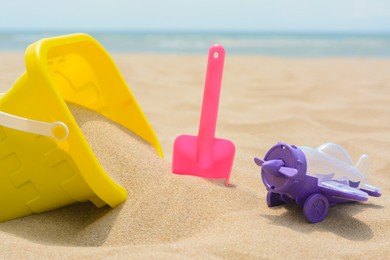 Photo of Set of colorful beach toys on sand near sea, closeup