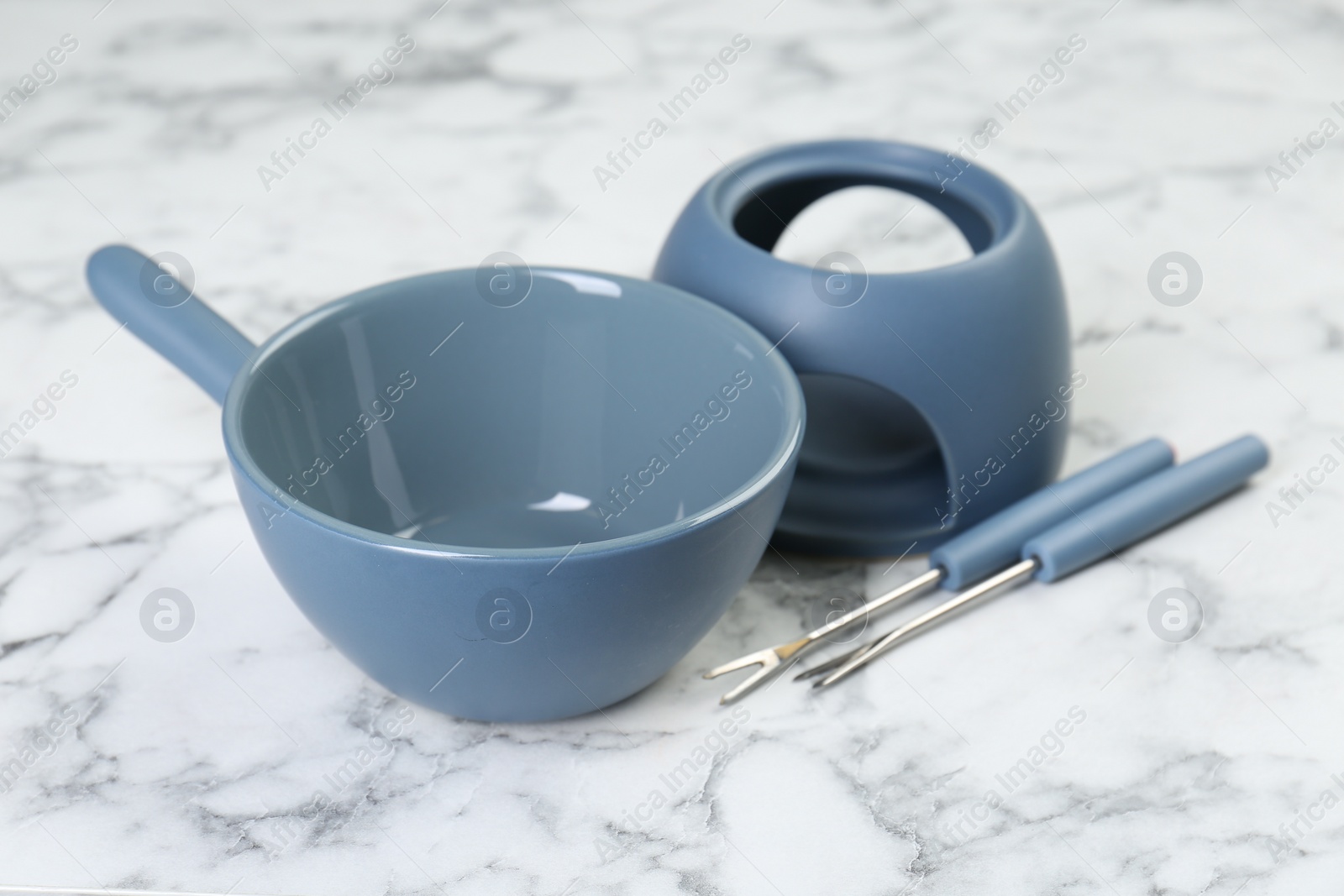 Photo of Fondue set on white marble table, closeup