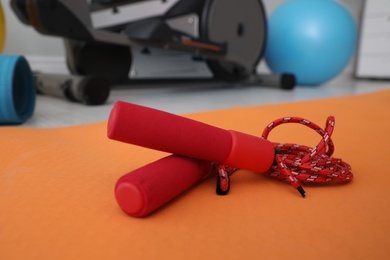 Photo of Skipping rope and sport equipment near elliptical machine indoors