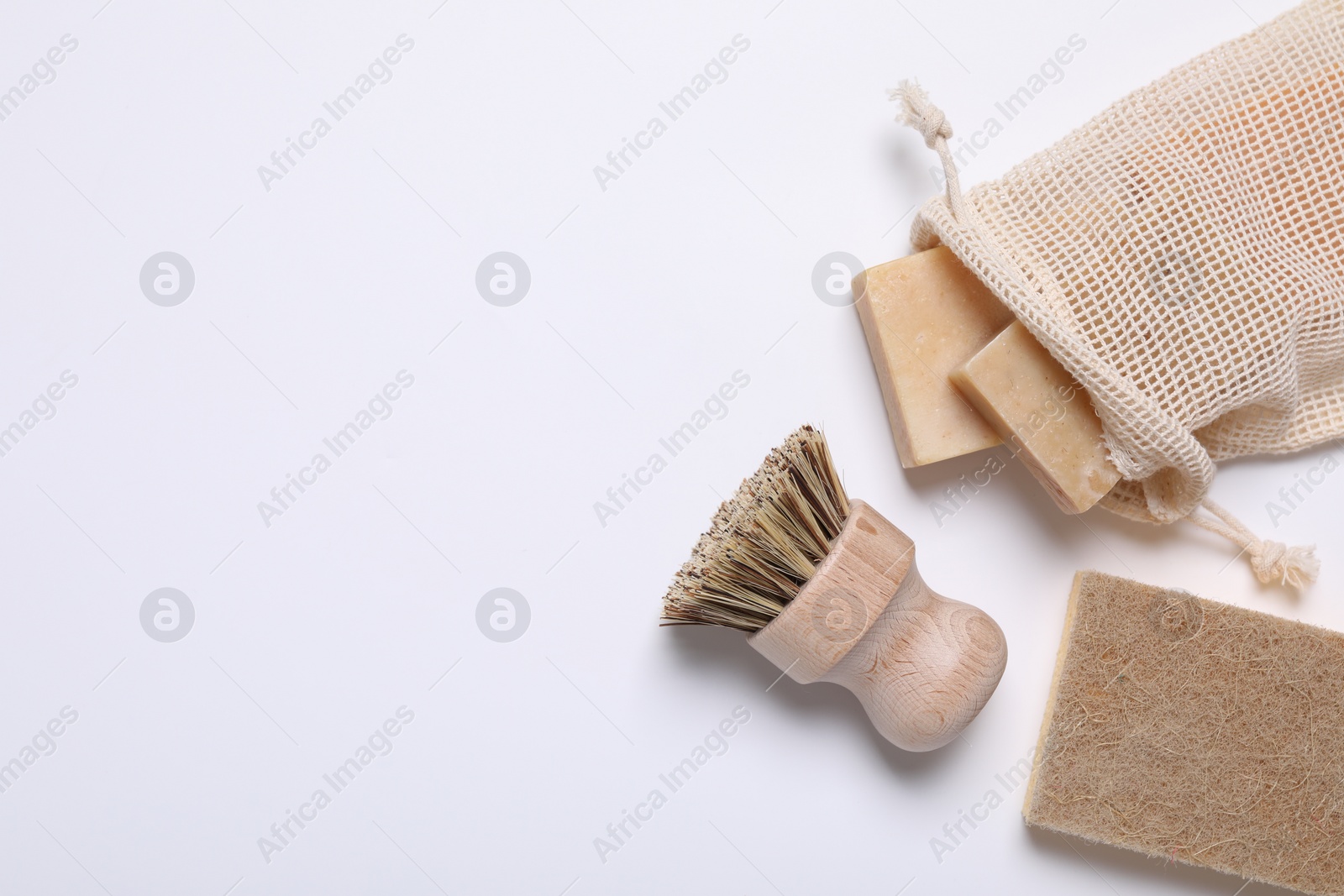 Photo of Cleaning brush, sponge and soap bars on white background, flat lay. Space for text