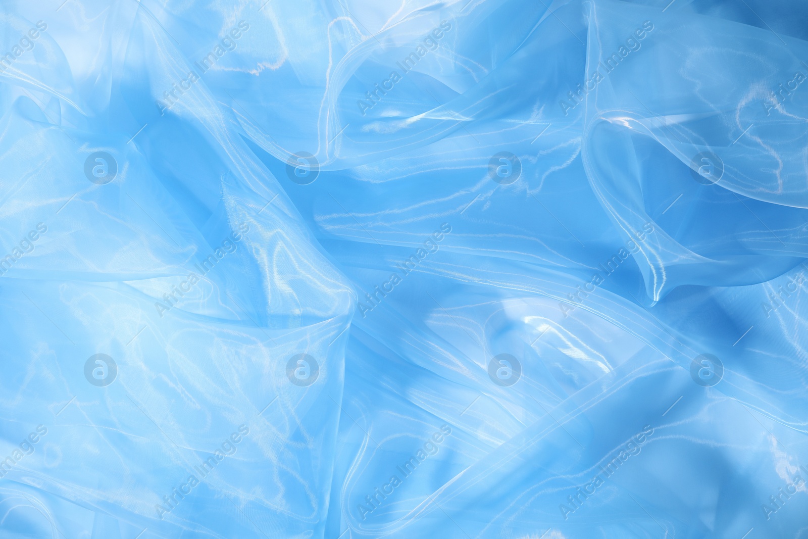 Photo of Beautiful light blue tulle fabric as background, closeup