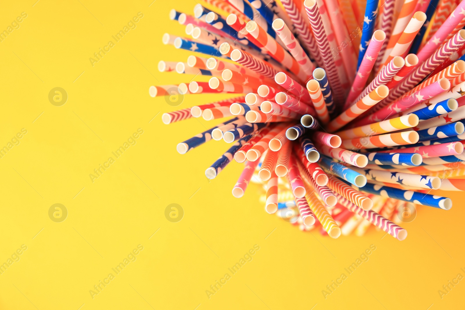 Photo of Many paper drinking straws on yellow background, top view. Space for text