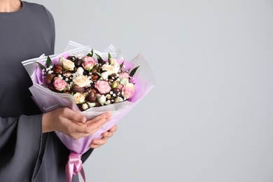 Photo of Woman with beautiful food bouquet on light grey background, closeup. Space for text