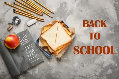 Image of Flat lay composition with lunch box, tasty sandwich and stationery on grey background