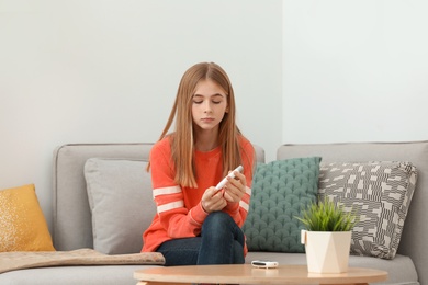 Photo of Teen girl using lancet pen at home. Diabetes control