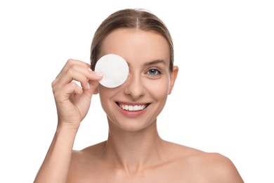 Smiling woman removing makeup with cotton pad on white background