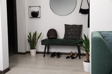 Photo of Stylish bench, shoes and backpack near light wall in hallway