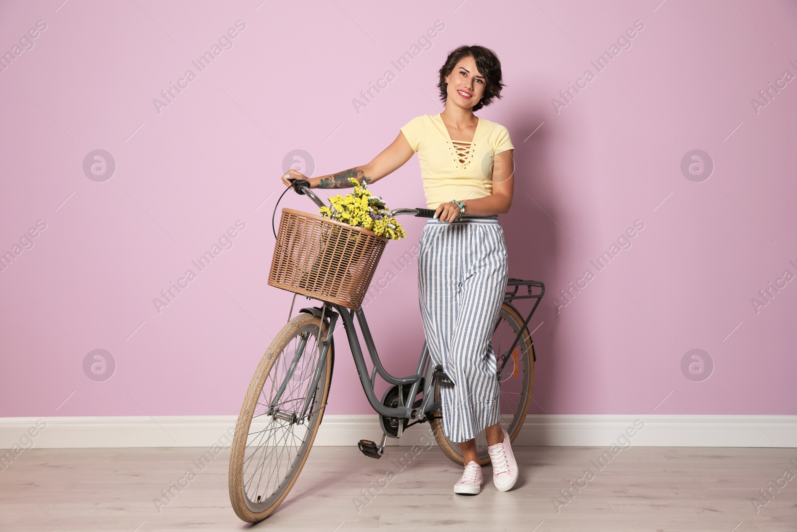 Photo of Portrait of beautiful young woman with bicycle near color wall