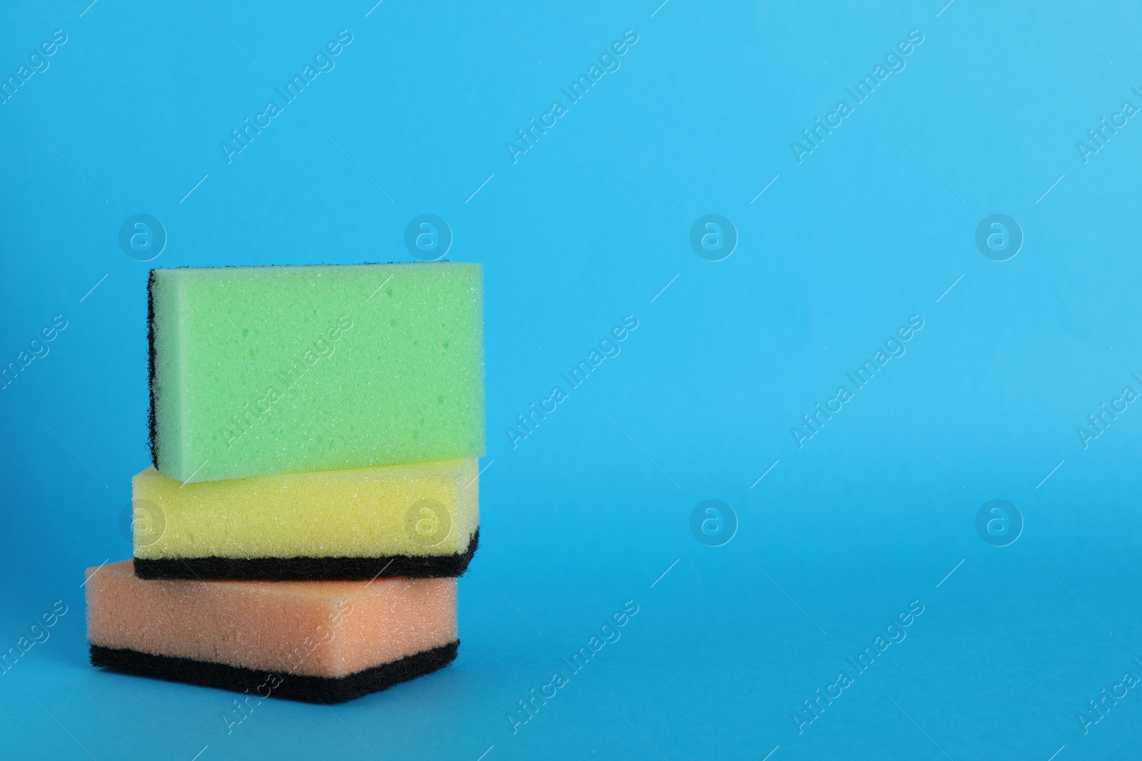 Photo of Color sponges on light blue background. Space for text
