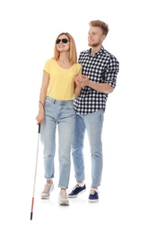 Young man helping blind person with long cane on white background