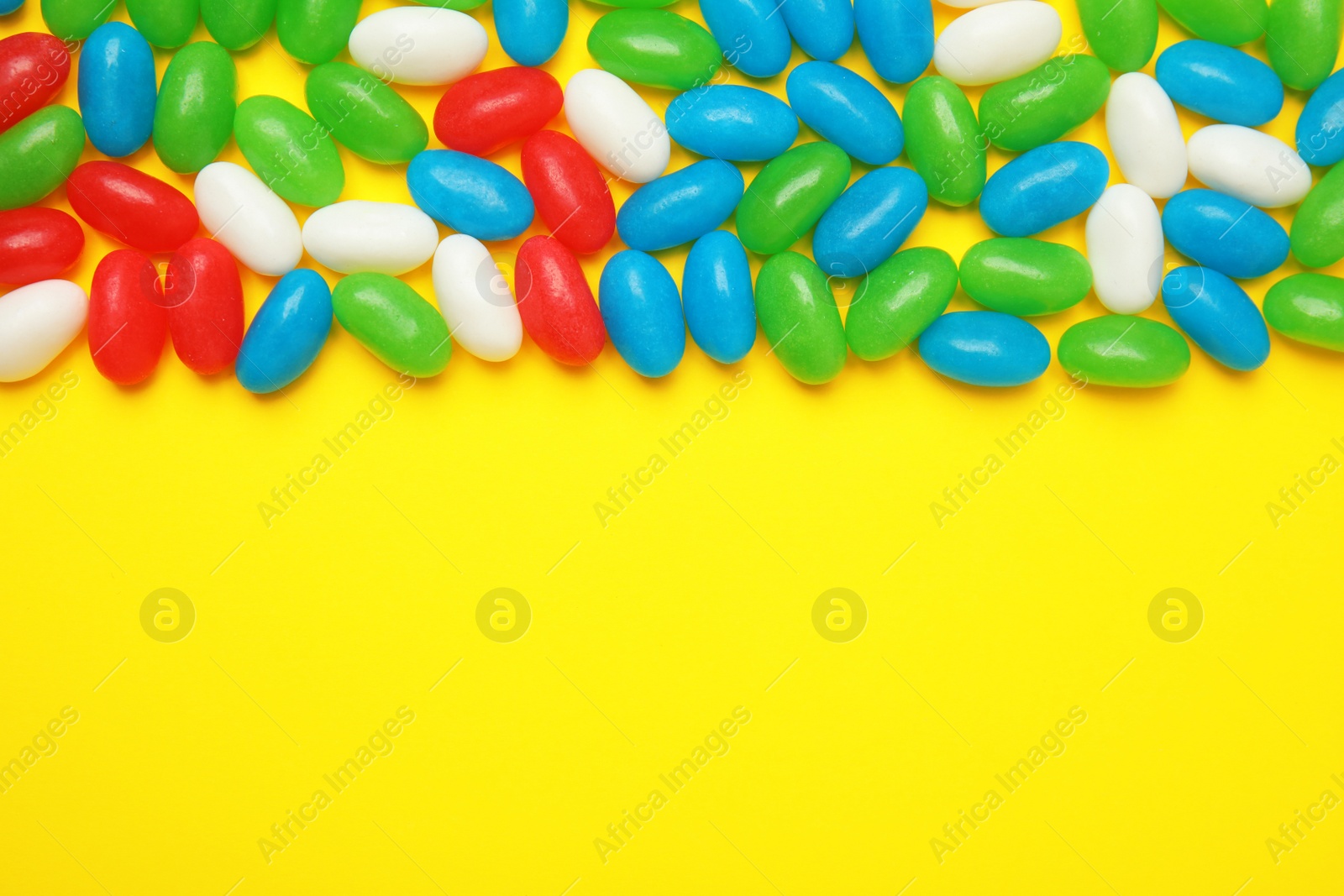 Photo of Flat lay composition with jelly beans on color background. Space for text