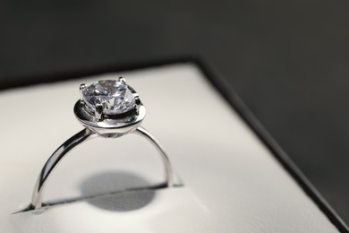 Photo of Beautiful engagement ring with gemstone in box on grey background, closeup