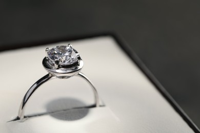 Beautiful engagement ring with gemstone in box on grey background, closeup