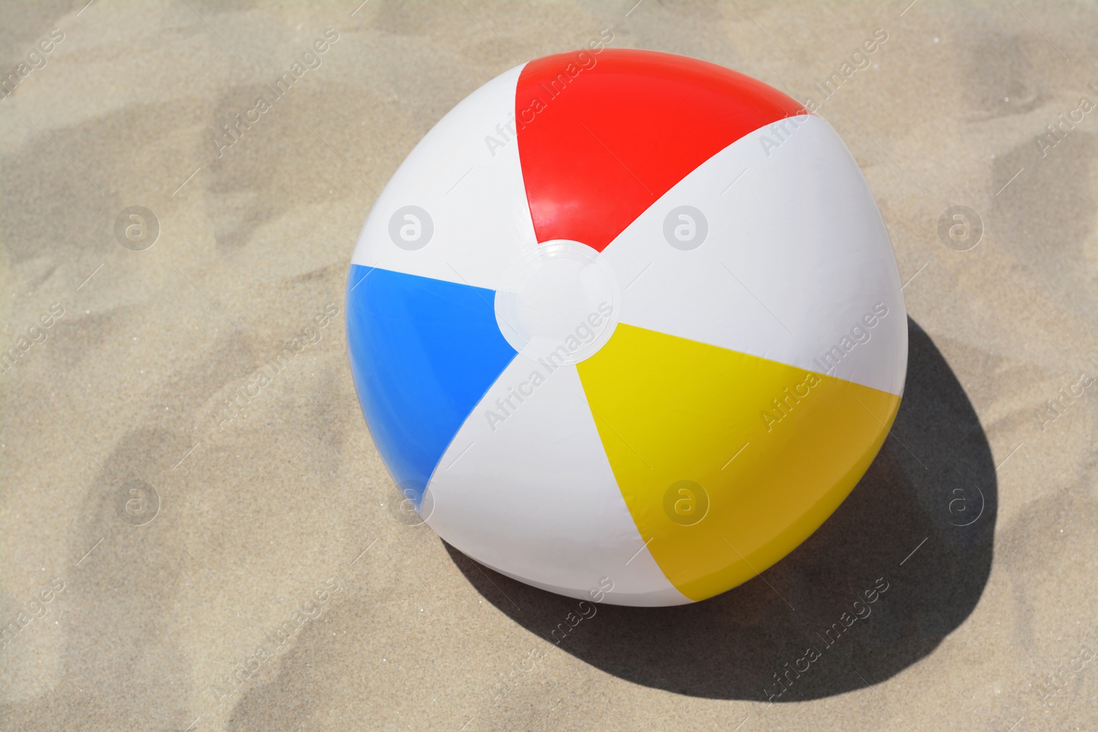 Photo of Colorful beach ball on sand, above view