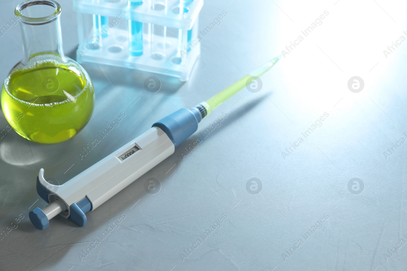 Photo of Laboratory analysis. Micropipette, flask and test tubes on grey table, space for text