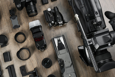 Flat lay composition with video camera and other equipment on wooden table