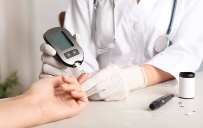 Photo of Doctor checking blood sugar level with glucometer at table. Diabetes test