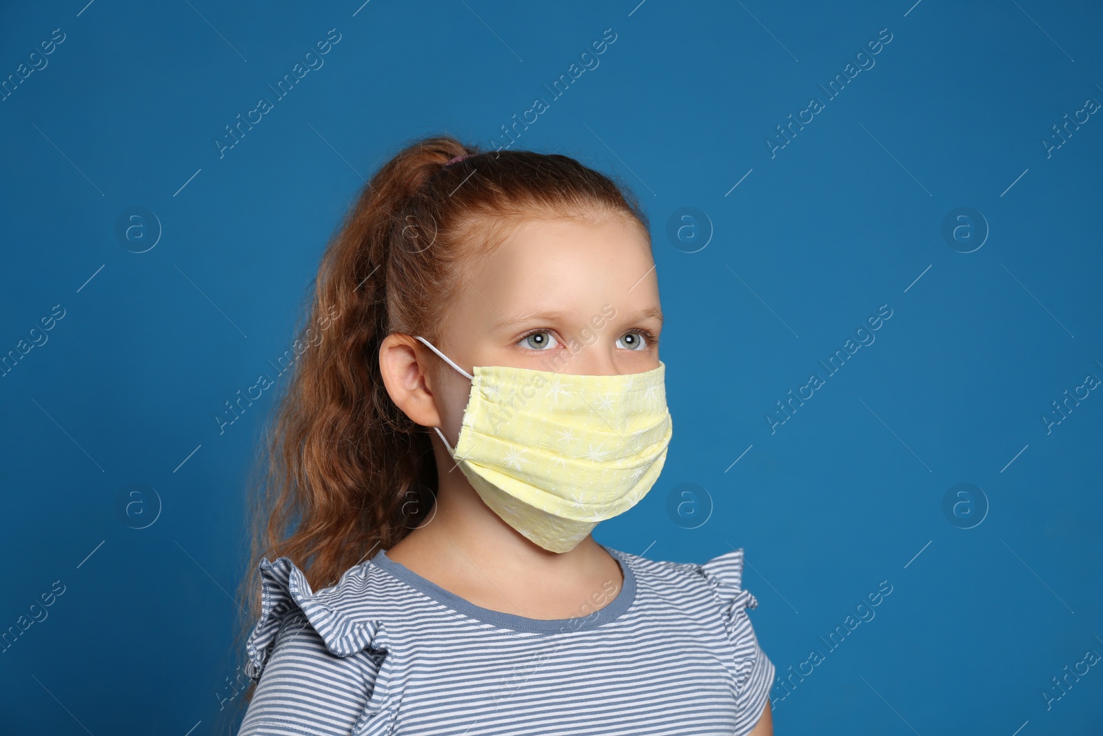 Photo of Preteen girl in protective face mask on blue background