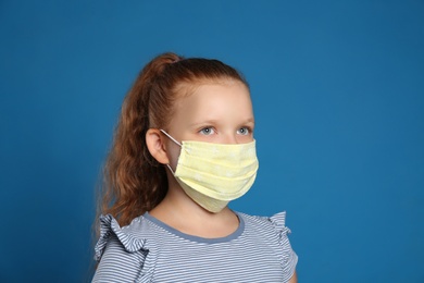 Photo of Preteen girl in protective face mask on blue background