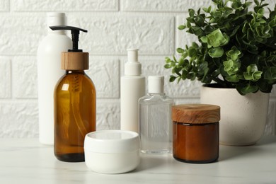 Photo of Bath accessories. Personal care products on white table near brick wall