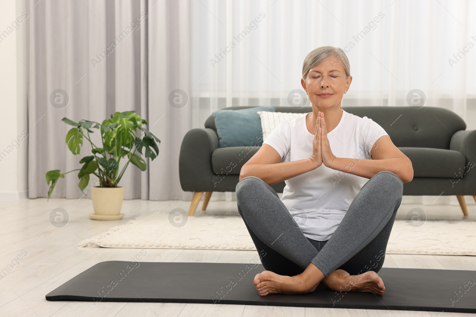 Photo of Senior woman practicing yoga on mat at home