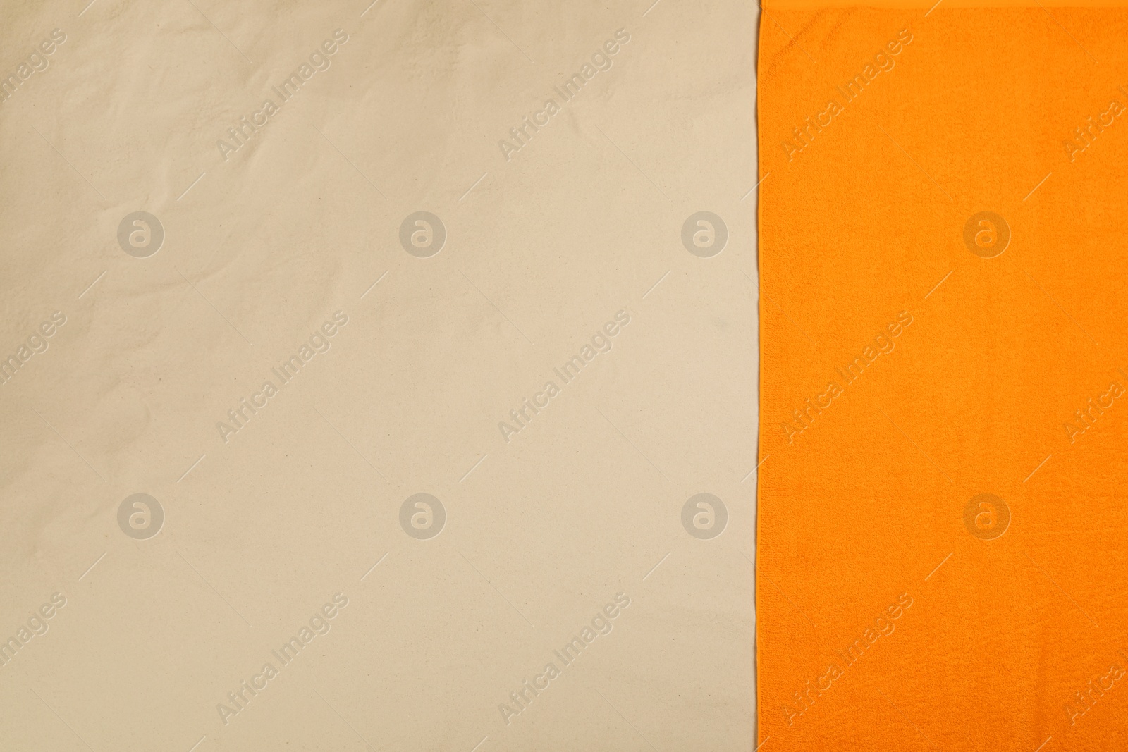 Photo of Orange beach towel on sand, top view. Space for text