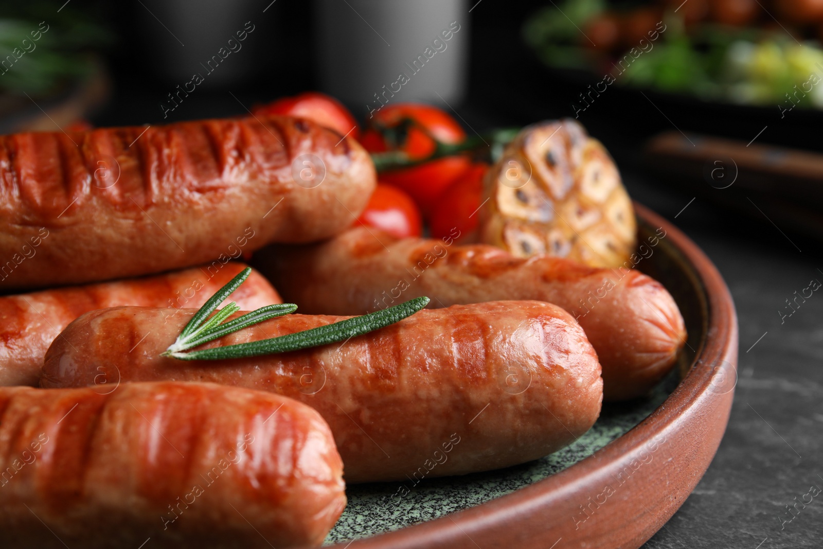 Photo of Tasty grilled sausages served on black table, closeup