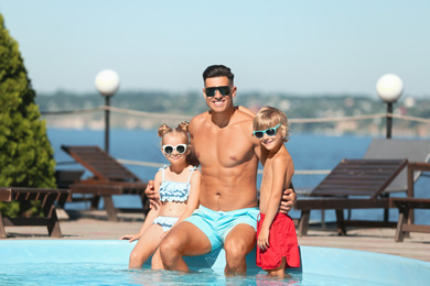 Photo of Happy man with his children at poolside on sunny summer day