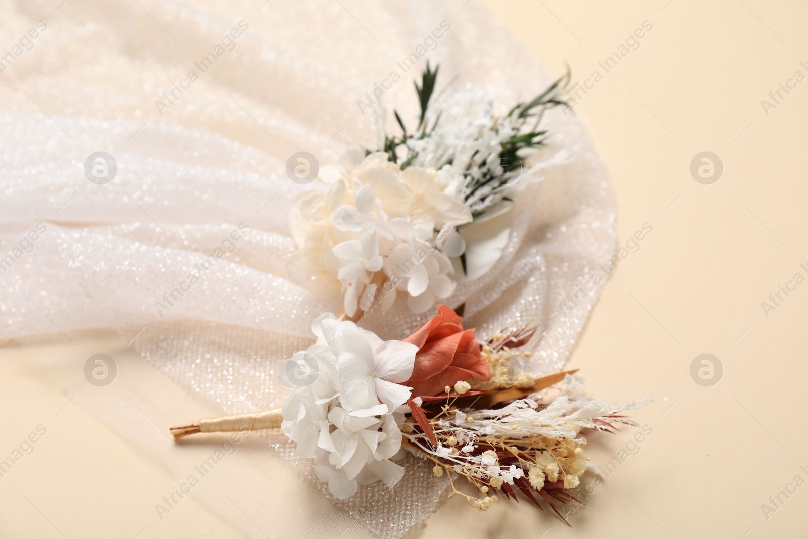 Photo of Stylish boutonniere and white fabric on beige background, closeup