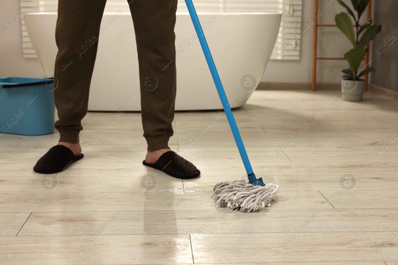 Photo of Man cleaning floor with mop indoors, closeup