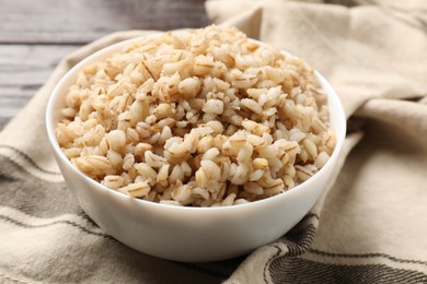 Photo of Delicious pearl barley in bowl on table, closeup