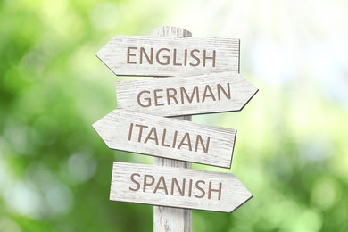 Image of Wooden signpost with names of different languages outdoors