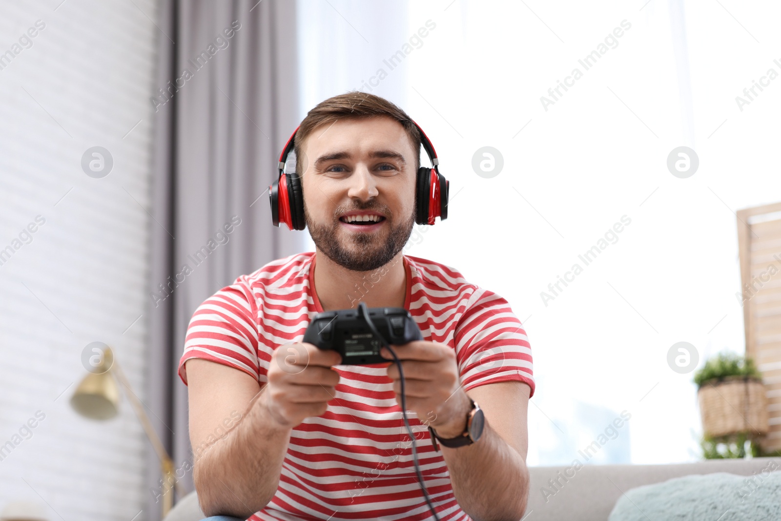 Photo of Young man playing video game at home