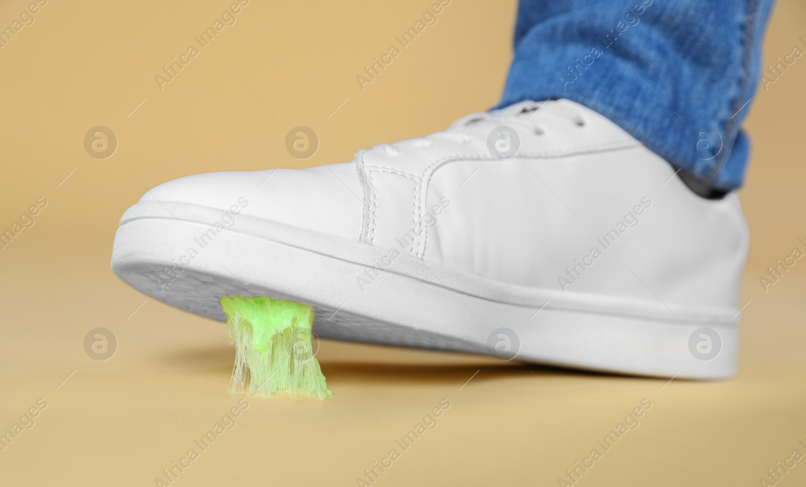 Photo of Person stepping into chewing gum on light brown background, closeup