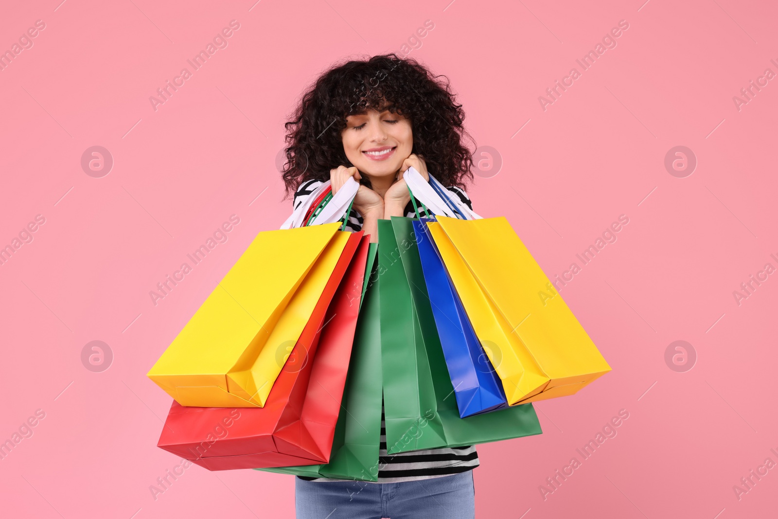 Photo of Happy young woman with shopping bags on pink background