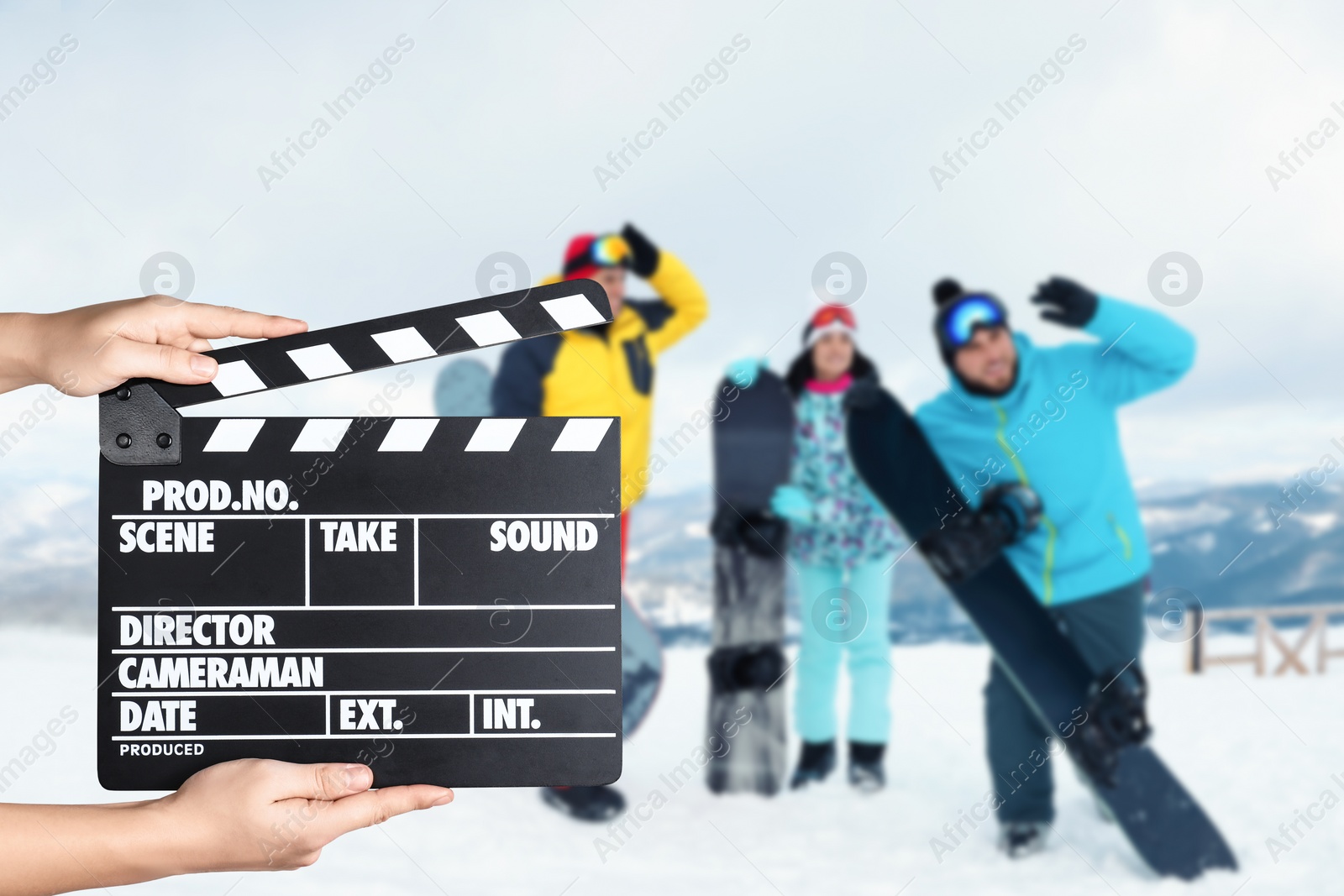 Image of Assistant holding clapperboard and people in snowy mountains, closeup. Cinema production 