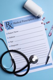 Photo of Medical prescription form, stethoscope, ampoules and pills on light blue background