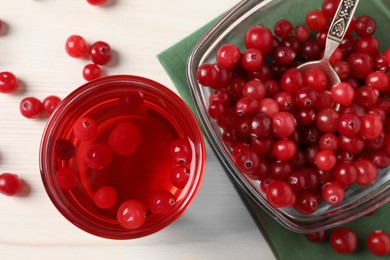 Photo of Tasty cranberry juice in glass and fresh berries on white wooden table, top view