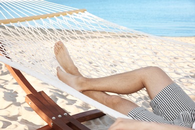 Photo of Young man resting in hammock at seaside. Summer vacation