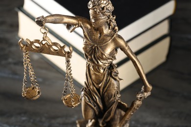 Photo of Symbol of fair treatment under law. Figure of Lady Justice and books on grey textured table, closeup