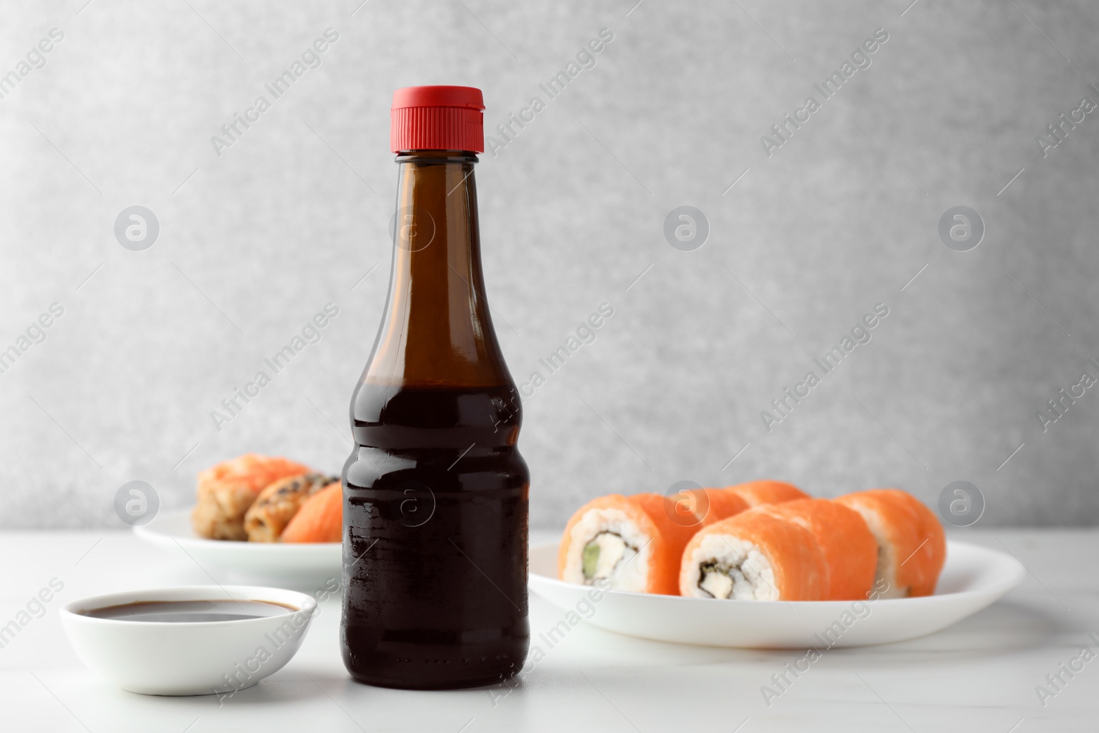 Photo of Tasty soy sauce and different types of sushi on white table