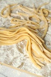 Photo of Raw homemade pasta and flour on table, closeup