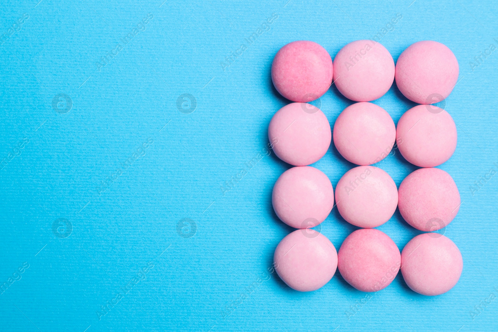 Photo of Pink bubble gums on blue background, flat lay. Space for text