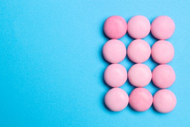 Photo of Pink bubble gums on blue background, flat lay. Space for text